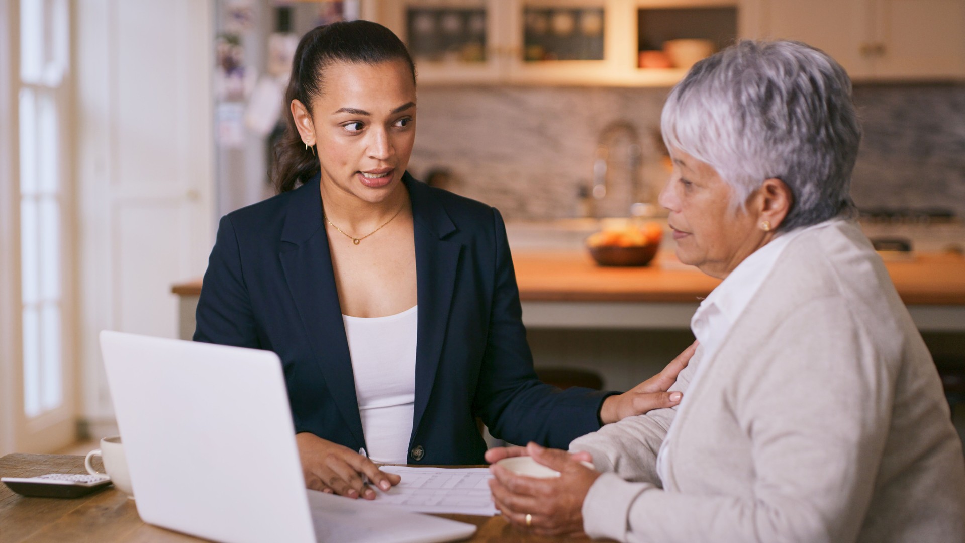 Shot of a consultant going through paperwork during a meeting with a senior woman at home